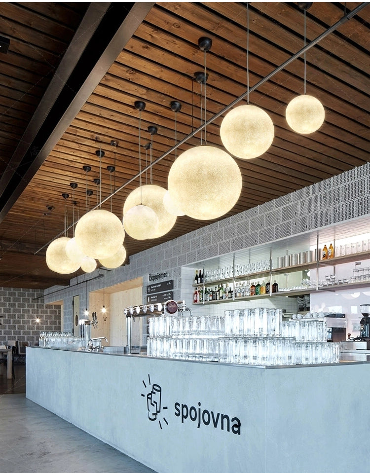 Kiven Lunar Pendant Lights in a bar setting, textured sphere design; 'spojovna' logo visible. Ideal for commercial use.