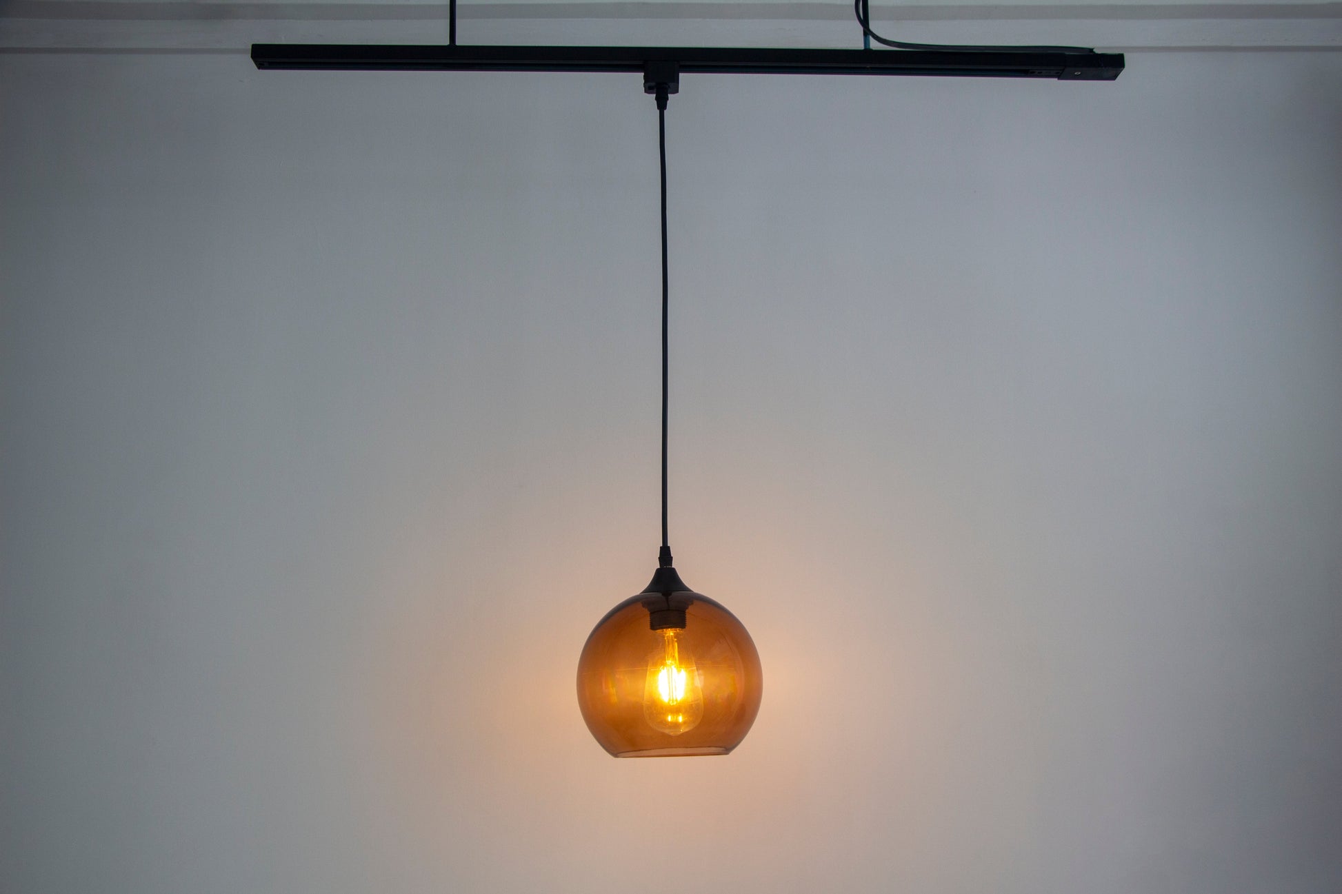 Modern track light pendant with amber glass globe and Edison bulb. Kiven Lighting for track lighting.