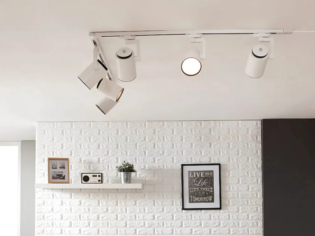 A modern, minimalist living room with a white brick wall, track lighting, and decorative wall art highlighting the message.