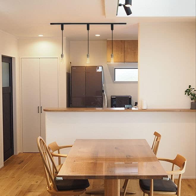 Black retractable track lighting pendants above dining table. Industrial lighting with Edison bulbs.