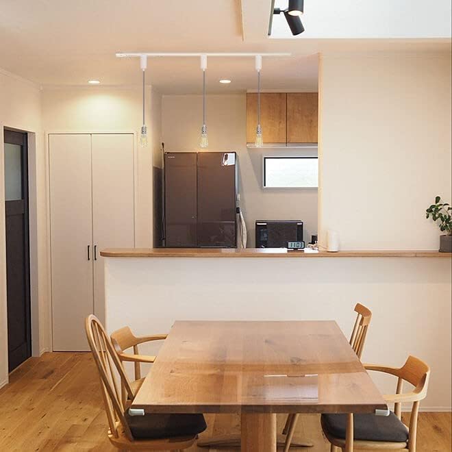 White track lighting pendants above a wooden dining table with Edison bulbs in a modern dining setting.