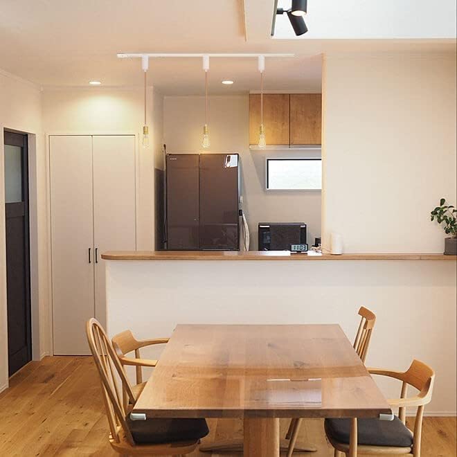 White track lighting pendants with Edison bulbs over wooden dining table. Modern kitchen lighting by Kiven.