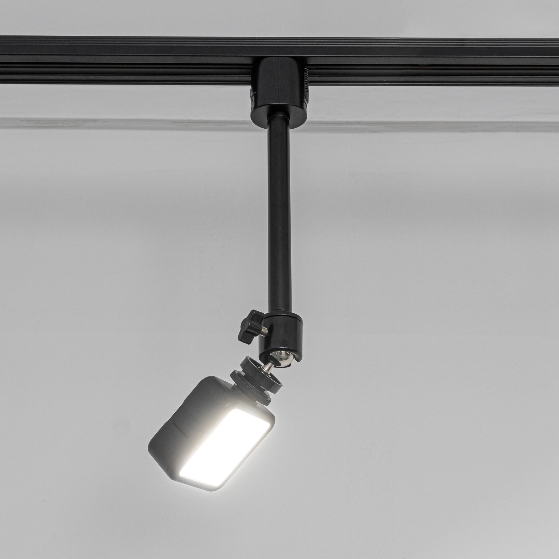 Black projector mount with adjustable spotlight, for ceiling track installation. Perfect for presentations and home theaters.