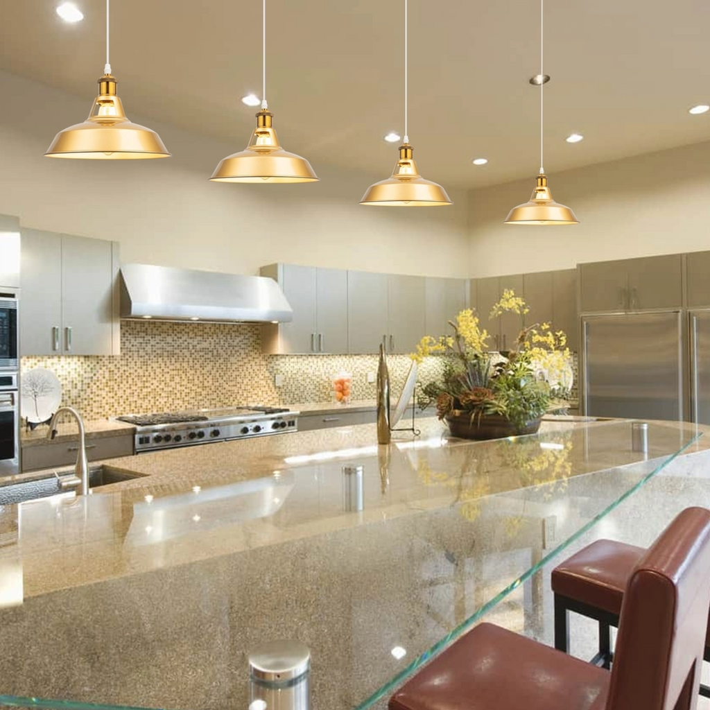 Four vintage gold metal dome pendant lights illuminated over a long kitchen breakfast bar, adjustable length hanging lamps for dining and ambient lighting