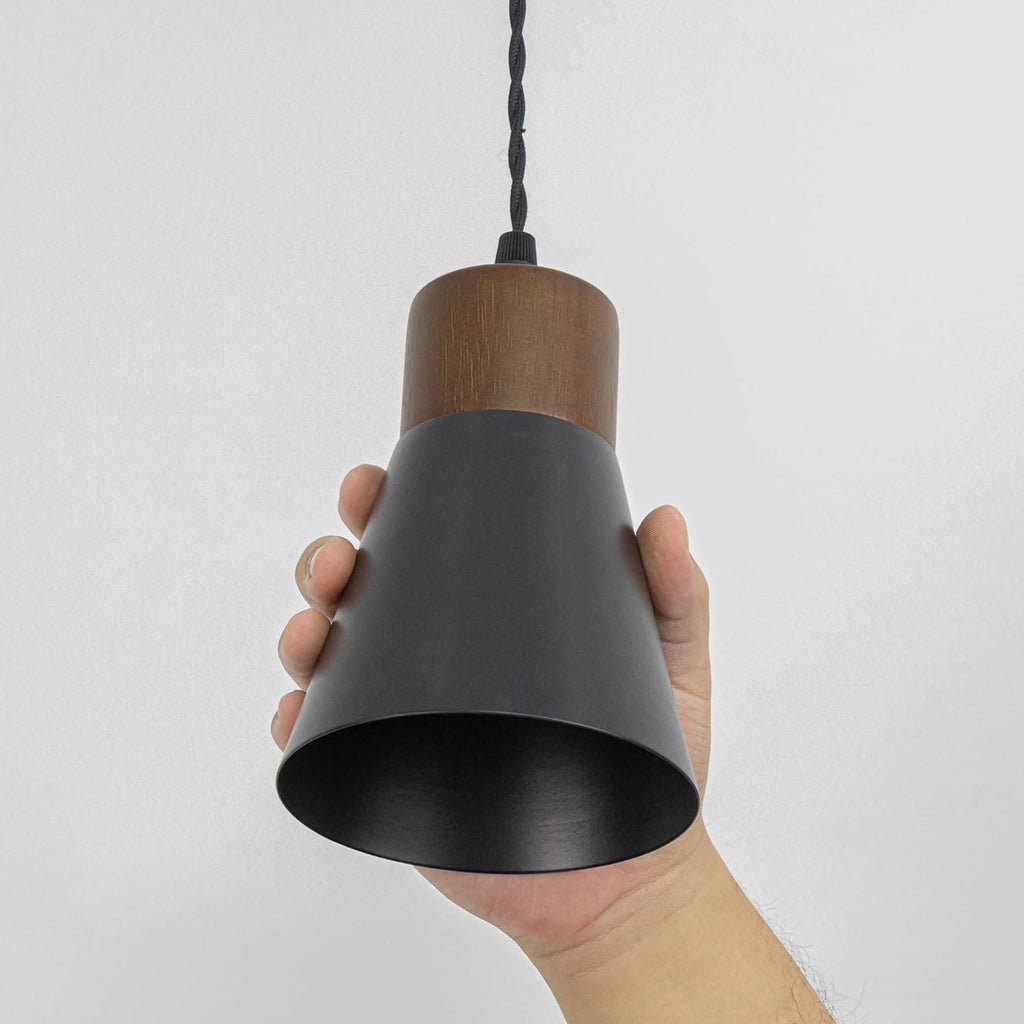 Black shade retro pendant track lights, with walnut base, illuminate a kitchen and dining area, vintage style.