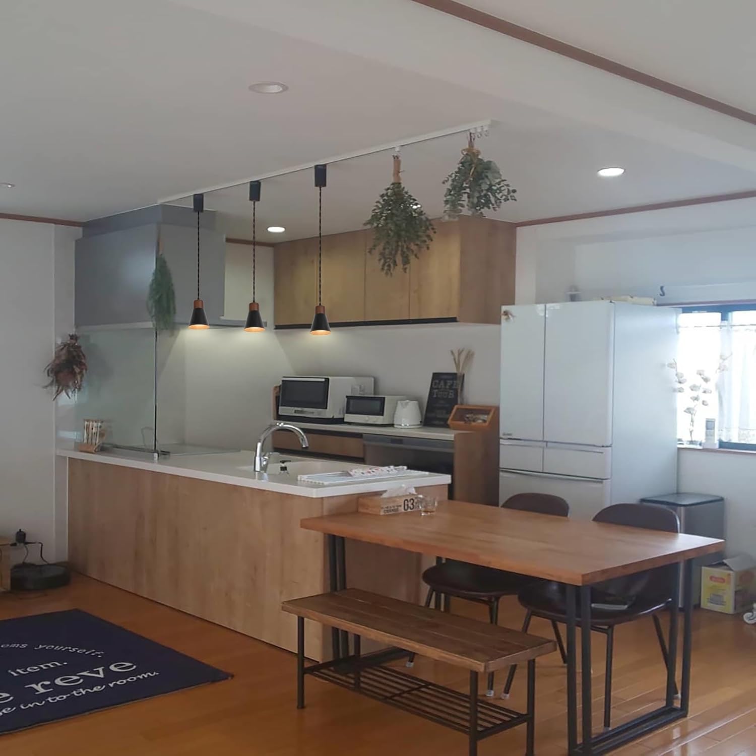Black shade retro pendant track lights, with walnut base, illuminate a kitchen and dining area, vintage style.