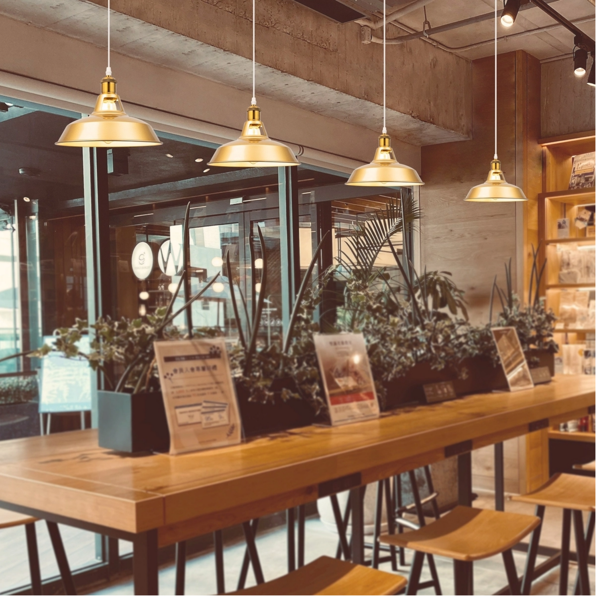 Set of 4 vintage gold metal track pendant lights with adjustable height hanging over a long wooden table in a rustic cafe, Scandinavian style commercial restaurant lighting