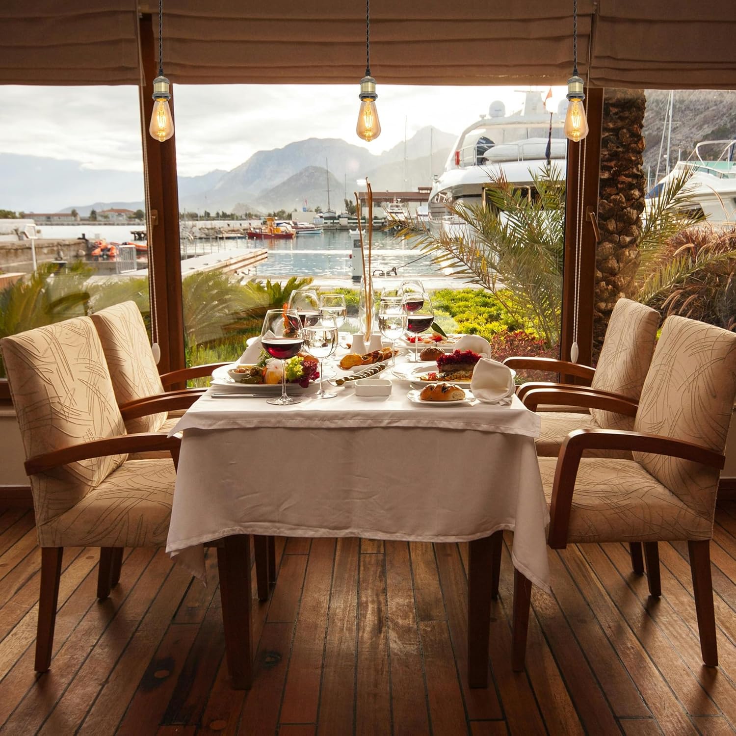 Kiven H-Type track pendant lighting in a cafe setting, over a table set for dinner, view to a harbor.