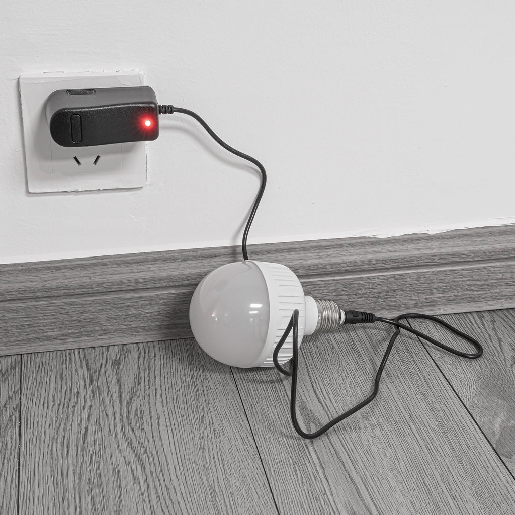Rechargeable smart LED bulb charging, connected to black charger in wall outlet.