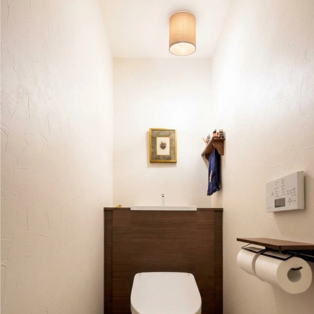 Renter-friendly linen drum lamp shade installed on toilet ceiling light in cozy bathroom