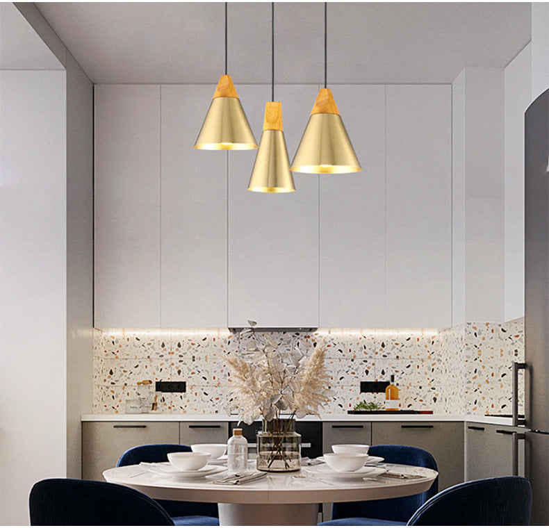 Gold cone pendant lights in kitchen, wooden top, perfect for dining. Modern, customizable lighting for home and business.