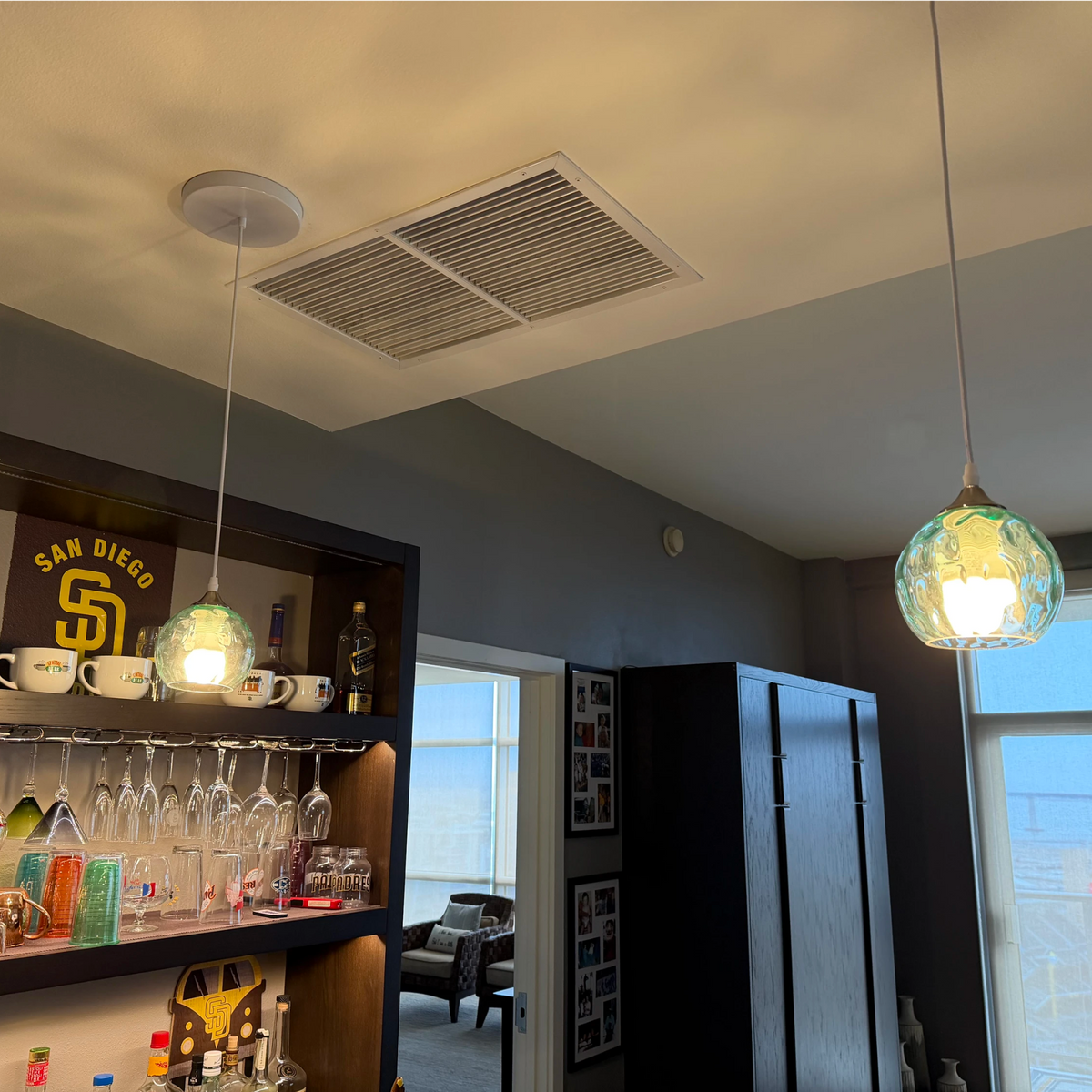 Customer installed photo: Green textured glass pendant lights above a home bar cabinet in modern home interior, real customer review picture of glass pendant lighting.