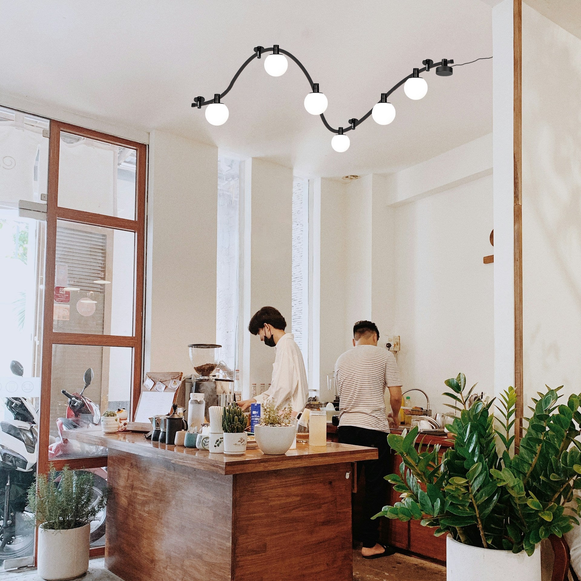 Black flexible track light with globe pendant lights in a cafe setting, showcasing customizable lighting.