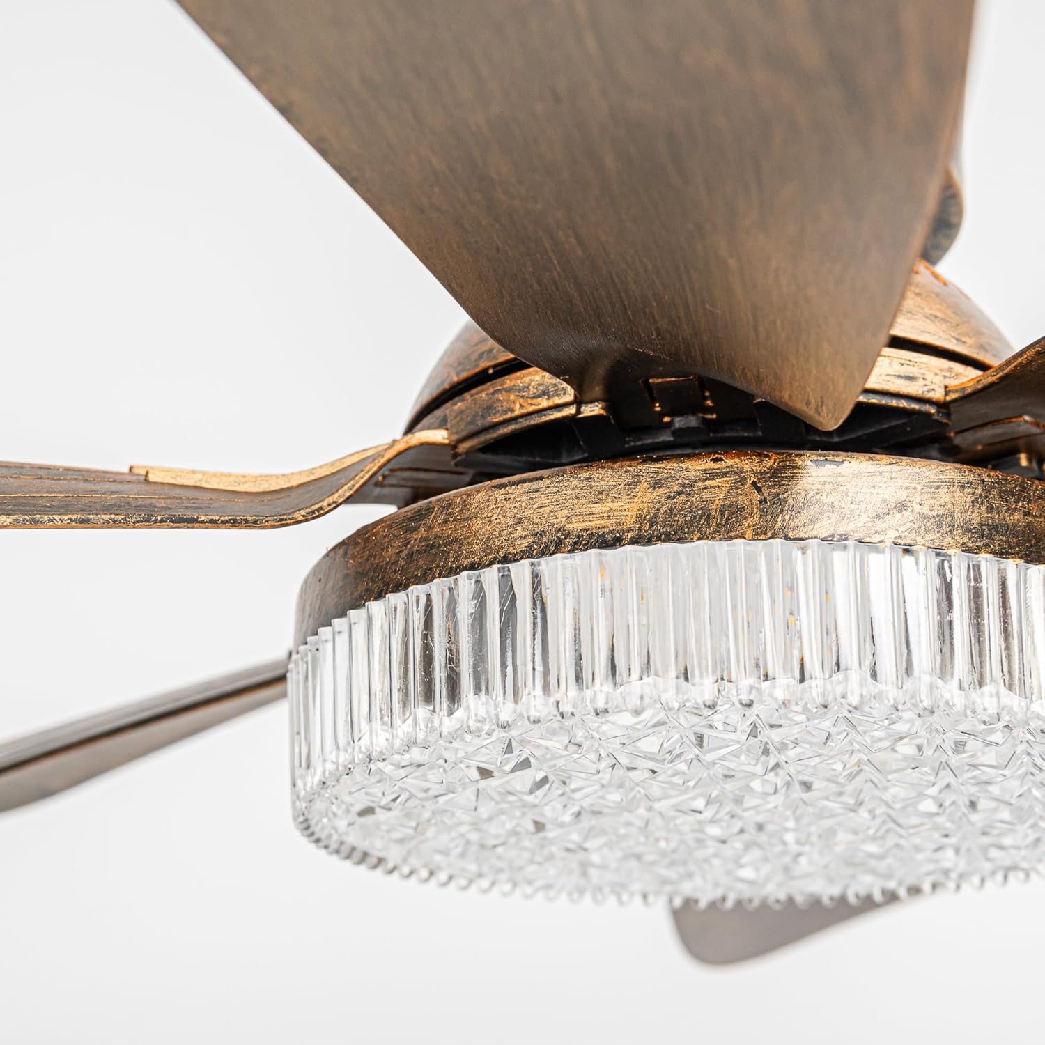 Close-up of the crystal-textured LED light cover on an antique bronze track fan, showing the intricate geometric glass pattern for elegant light refraction and the hand-brushed vintage metallic finish.