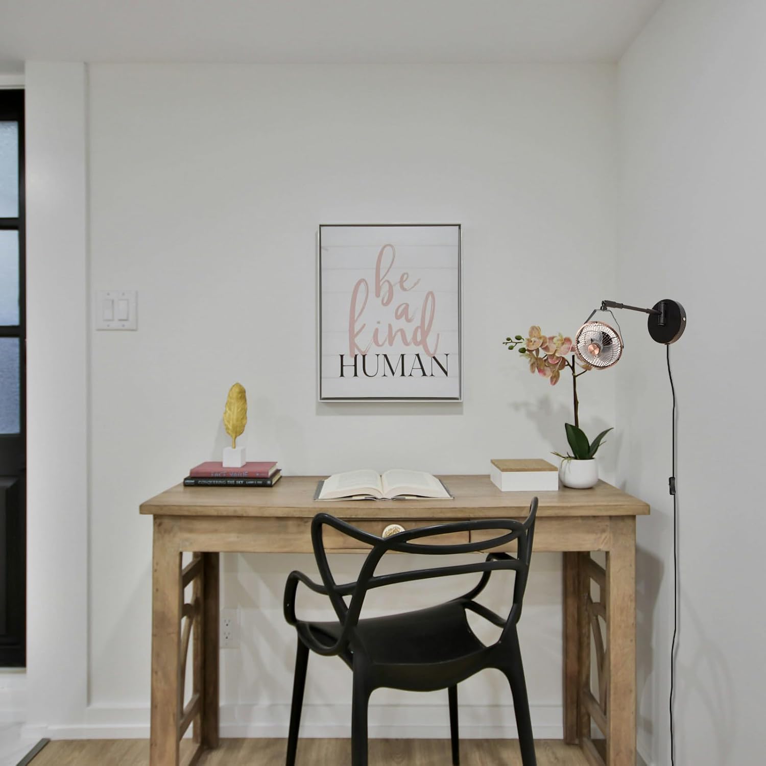 Industrial black wall mount fan with swing arm installed next to a home office wooden study desk