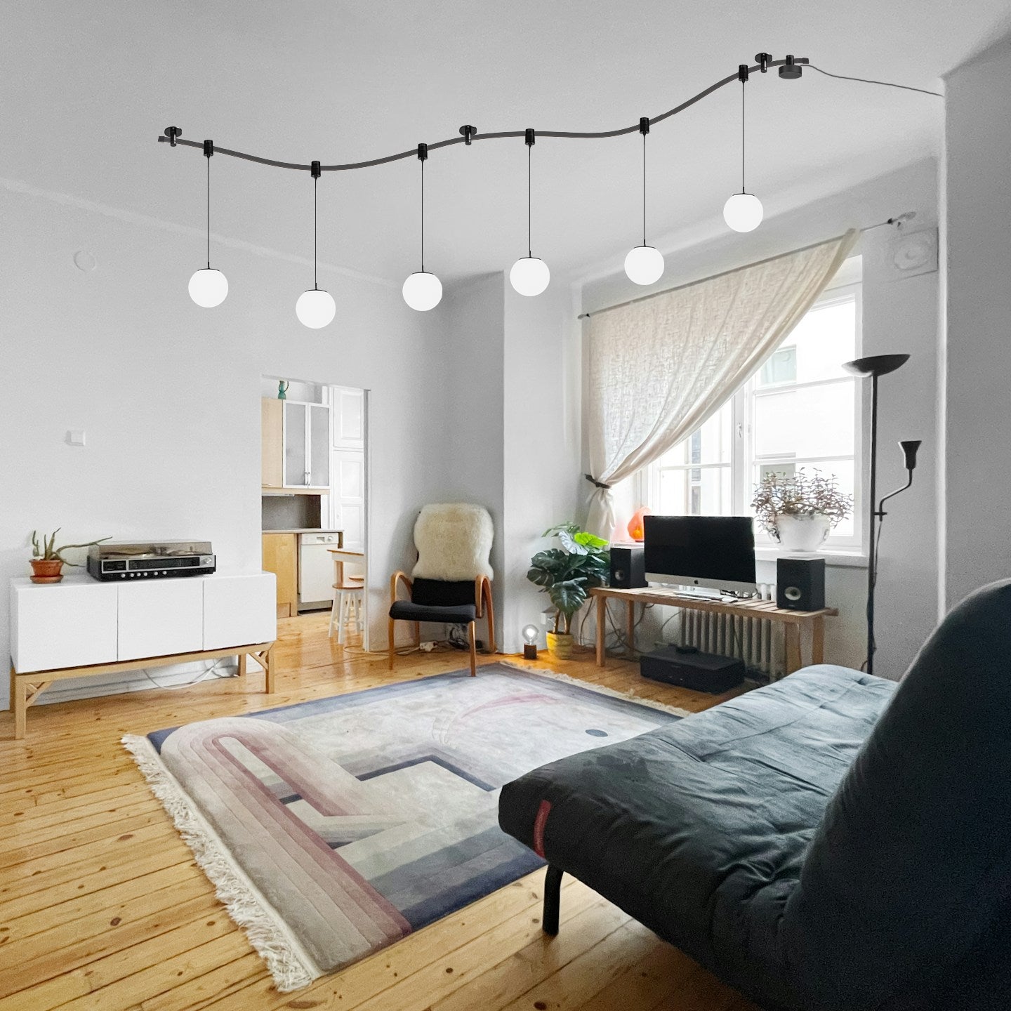 Black flexible track light with globe pendant lights in a living room setting, customizable lighting.