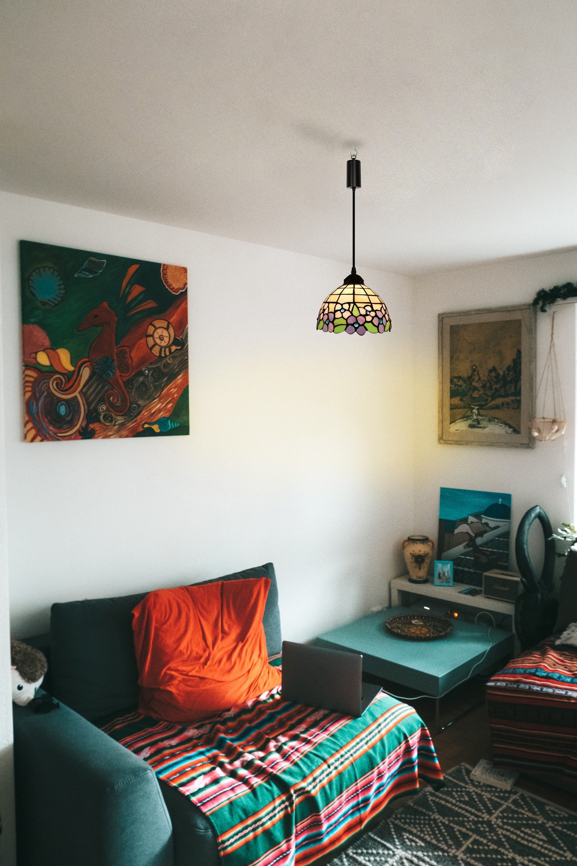 Tiffany pendant light with colorful glass shade, illuminating a living room. Battery operated adjustable cord pendant.